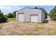 Detached outbuilding with two garage doors and gravel driveway on a sunny, partially grassy lot at 7056 E 171St St, Noblesville, IN 46062