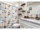Bathroom with granite counters, floating shelves with decor, and a unique shower curtain design at 747 Tuxedo Dr, Westfield, IN 46074