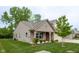 Charming exterior elevation of home featuring a covered porch, attached garage and green front lawn and plantings at 808 Heartland Ln, Brownsburg, IN 46112
