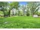 A lush green back yard with mature trees, a playground, and a storage shed at 820 S Eaglewood Dr, Zionsville, IN 46077