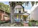 Inviting two-story home featuring a covered front porch with seating and mature trees at 847 N Park Ave, Indianapolis, IN 46202