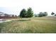 A large, grassy backyard featuring a small tree, a wood privacy fence, and a patio area at 895 Geronimo Dr, Greenfield, IN 46140