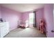 This pink Bedroom offers neutral carpet, a bright window and a white crib and dresser at 895 Geronimo Dr, Greenfield, IN 46140
