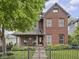 Charming red brick home with well-manicured landscaping and wrought iron fence at 914 N College Ave, Indianapolis, IN 46202