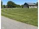 Landscaped lawn of gray brick home featuring a circular pattern and mature trees at 951 N Maiellen Dr, Greenfield, IN 46140