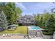 Stunning lakefront home featuring a pool, stone terrace, and lush landscaping with mature trees at 11715 Landings Dr, Indianapolis, IN 46256
