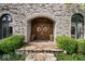 Charming stone home entrance with a decorative wood door and manicured landscaping at 11715 Landings Dr, Indianapolis, IN 46256