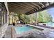 Covered stone patio featuring a plunge pool, seating, and views of the backyard and main pool at 11715 Landings Dr, Indianapolis, IN 46256