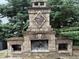 Outdoor brick fireplace with a diamond shape design and storage on both sides, surrounded by lush greenery at 13217 E 131St St, Fishers, IN 46037