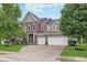 Inviting two-story home features a three-car garage, red siding and a well-manicured lawn at 14075 Knightstown E Dr, Carmel, IN 46033