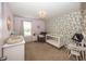 Cozy Bedroom features soft lavender walls and charming floral wallpaper with a plush armchair and white crib at 16419 Connolly Dr, Westfield, IN 46074