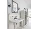 This bright bathroom features two pedestal sinks, black sconces, mirrors, and white wainscoting with light blue paint above at 1799 Hourglass Dr, Carmel, IN 46032