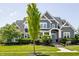 Charming gray two-story home with manicured lawn, blue door and mature tree at 1799 Hourglass Dr, Carmel, IN 46032