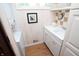 Functional laundry room with white cabinets, modern washer/dryer unit, and wooden floor at 232 S Audubon Rd, Indianapolis, IN 46219