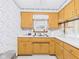 Traditional kitchen with wood cabinets, laminate counters, and floral wallpaper at 25 N Mustin Dr, Anderson, IN 46012