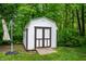 A white storage shed nestled in a lush, wooded backyard provides extra space for tools and equipment at 3230 Amherst St, Indianapolis, IN 46268