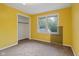 Bedroom featuring bright yellow walls, carpeted flooring, and a closet with natural light from the window at 502 S Harrison St, Alexandria, IN 46001