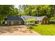 Beautiful exterior view of a red brick home with a manicured lawn and a gravel driveway framed by mature trees at 535 W 93Rd St, Indianapolis, IN 46260