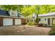 View of a two-car garage attached to a red brick home with gravel driveway and rear exterior entrance at 535 W 93Rd St, Indianapolis, IN 46260