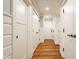 Bright hallway featuring hardwood floors, white wainscoting, and ample storage closets at 535 W 93Rd St, Indianapolis, IN 46260