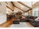 Open-concept living room featuring hardwood floors, a brick fireplace, and a comfortable leather sectional sofa and large windows at 535 W 93Rd St, Indianapolis, IN 46260
