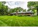 Large, green backyard featuring a well-kept lawn, mature trees, and a brick home with landscaping at 5415 Kilmer Ln, Indianapolis, IN 46250