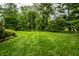 Lush green backyard with mature trees, landscaped garden beds, and a neatly mowed lawn at 5415 Kilmer Ln, Indianapolis, IN 46250