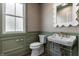 Bathroom with green paneling, unique mirror, sink with golden fixtures and hardwood floor at 5682 Broadway St, Indianapolis, IN 46220