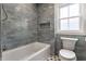 Bathroom with grey subway tile, soaking tub, patterned tile flooring, and a bright window at 5682 Broadway St, Indianapolis, IN 46220