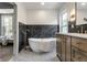 Elegant bathroom featuring freestanding tub, wood vanity, striking black accent tiles, and modern fixtures at 5682 Broadway St, Indianapolis, IN 46220