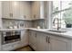Bright kitchen features white cabinets, light countertops, tile backsplash, and stainless steel microwave at 5682 Broadway St, Indianapolis, IN 46220