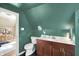 Bathroom featuring green walls, vanity, toilet, and view to an adjoining bedroom at 710 N Spring St, Greenfield, IN 46140