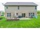 Back exterior of the house featuring a brick patio with outdoor furniture, a lush lawn, and mature landscaping at 7322 Stones River Dr, Indianapolis, IN 46259