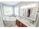 Bathroom with double vanity, soaking tub with a window, and stylish lighting at 7322 Stones River Dr, Indianapolis, IN 46259