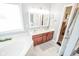 Bathroom featuring double vanity, soaking tub with a window, stylish lighting at 7322 Stones River Dr, Indianapolis, IN 46259