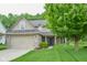 Lovely home featuring a lush green lawn, mature tree, brick accents, and a welcoming front entrance at 7322 Stones River Dr, Indianapolis, IN 46259