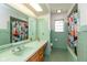 Green bathroom features a large mirror, colorful shower curtain, and a tiled floor at 7401 Spring Mill Rd, Indianapolis, IN 46260
