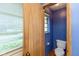 Blue-walled half-bath features a window, a white commode, and a blond wood door at 7401 Spring Mill Rd, Indianapolis, IN 46260