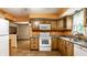 Well-lit kitchen with wooden cabinets, white appliances and access to other living spaces at 7580 Sherry Ln, Brownsburg, IN 46112