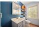 Bathroom featuring a vanity, toilet, a blue wall, and a window letting in natural light at 7910 N College Ave, Indianapolis, IN 46240