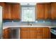 Close-up of kitchen showcasing stainless steel dishwasher, faucet, and wooden cabinetry at 7910 N College Ave, Indianapolis, IN 46240