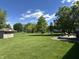 Well-maintained backyard features lush green grass, mature trees, a storage shed, and a stone patio with seating at 10 Sara Ct, Whiteland, IN 46184