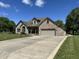 Spacious brick home with a wide driveway, lush green lawn, and mature trees on a sunny day at 10 Sara Ct, Whiteland, IN 46184