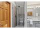 Main bathroom with a modern glass shower, gray tiling, and gray vanity with double sinks at 10418 Forest Creek Dr, Indianapolis, IN 46239