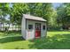 Well-maintained shed with a red door, set against a backdrop of mature trees and green grass at 10418 Forest Creek Dr, Indianapolis, IN 46239