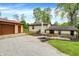 Home exterior with gravel driveway, detached garage, stone landscape wall, and wooded scenery at 10972 W Old Nashville Rd, Columbus, IN 47201