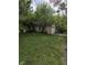 View of the detached two car garage from the yard surrounded by trees and vegetation at 1168 N Gladstone Ave, Indianapolis, IN 46201