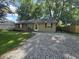 Charming single-story home with gravel drive, manicured lawn and mature trees offering shade at 1263 Barefoot Trl, Greenwood, IN 46142