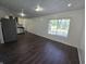 Open concept living room with dark wood floors, white walls, view into kitchen, and bright window at 1263 Barefoot Trl, Greenwood, IN 46142