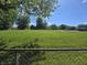 View of large lot with grassy field and distant houses, partially enclosed by a chain link fence at 1263 Barefoot Trl, Greenwood, IN 46142